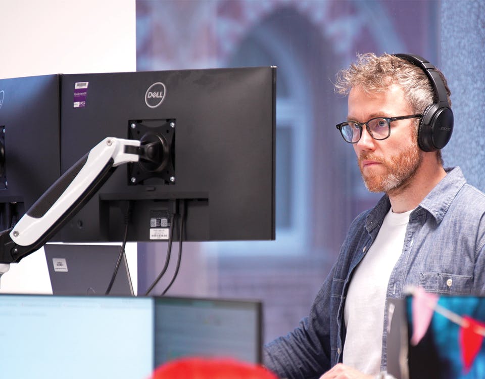 Person wearing headphones looking at computer monitor