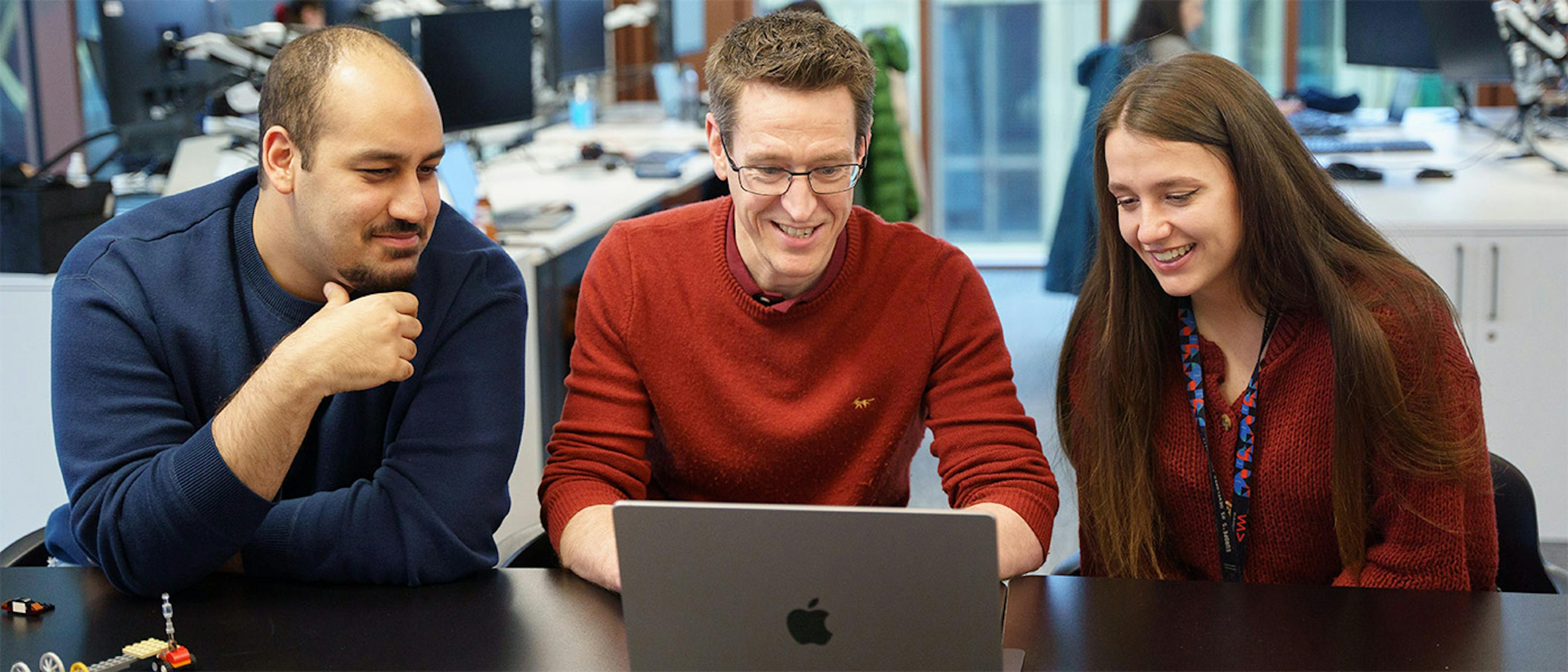 Three people looking at a computer screen in an office setting