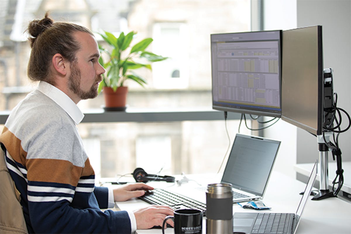 Person sitting at laptop and monitor