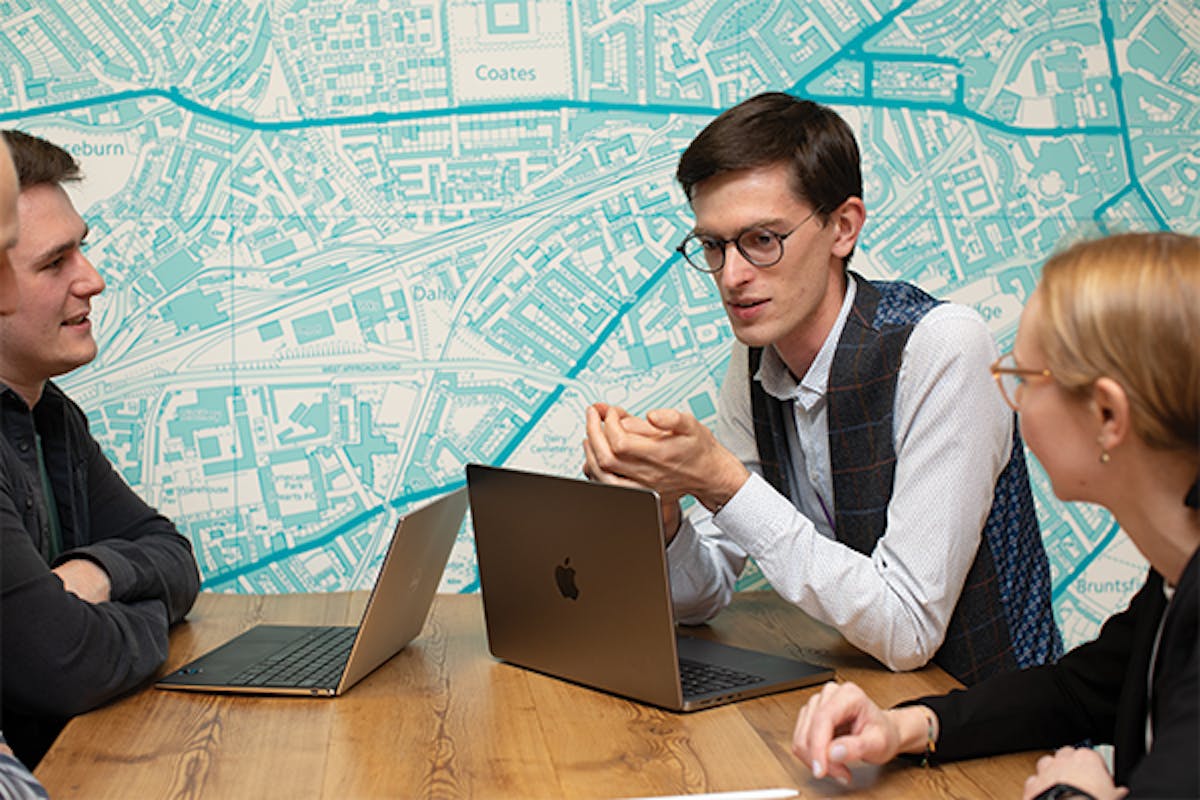 People in discussion with each other on a table with two laptops