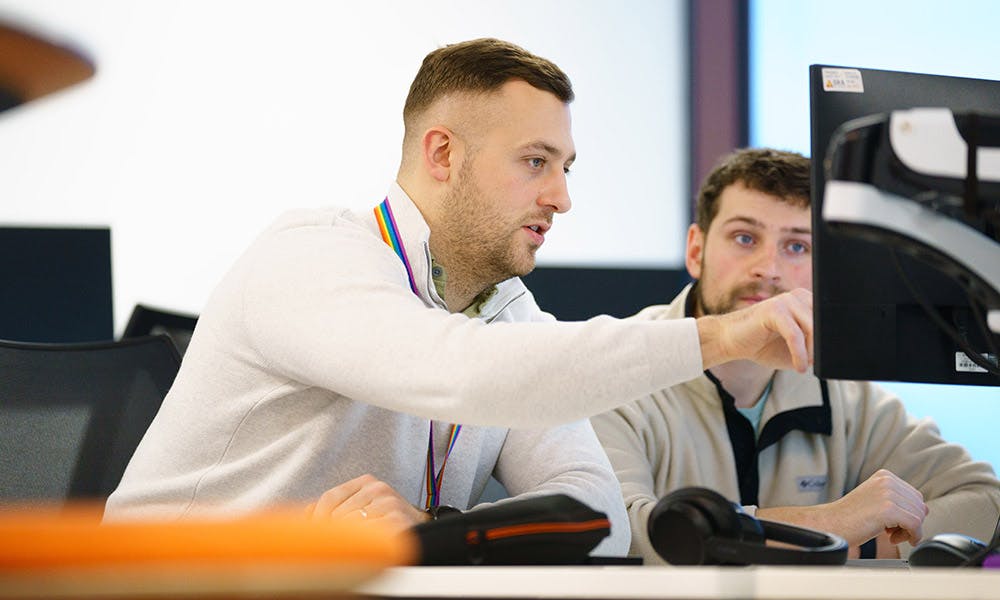 Two developers discussing code on a computer screen