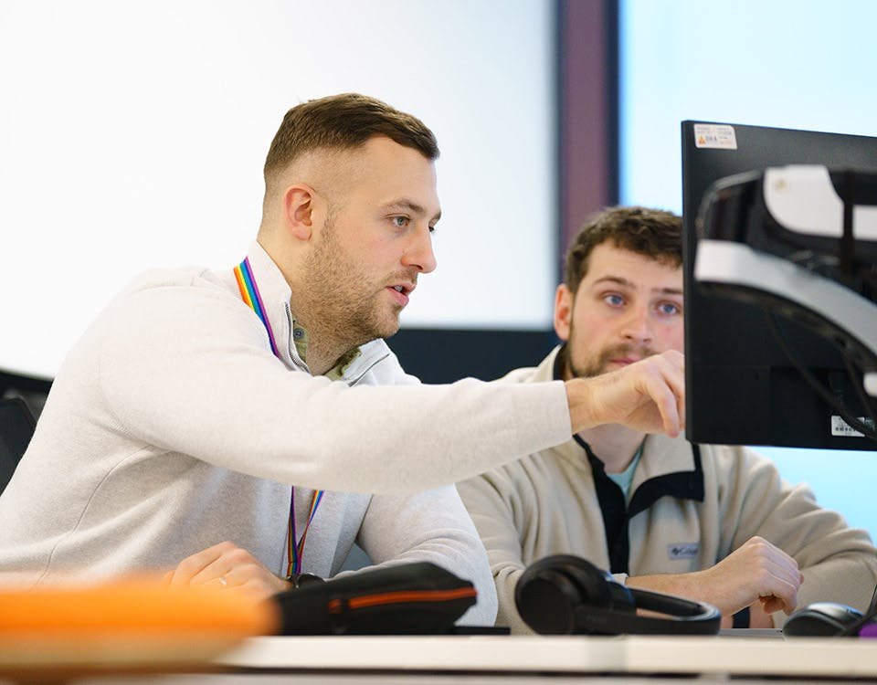 Two developers discussing code on a computer screen