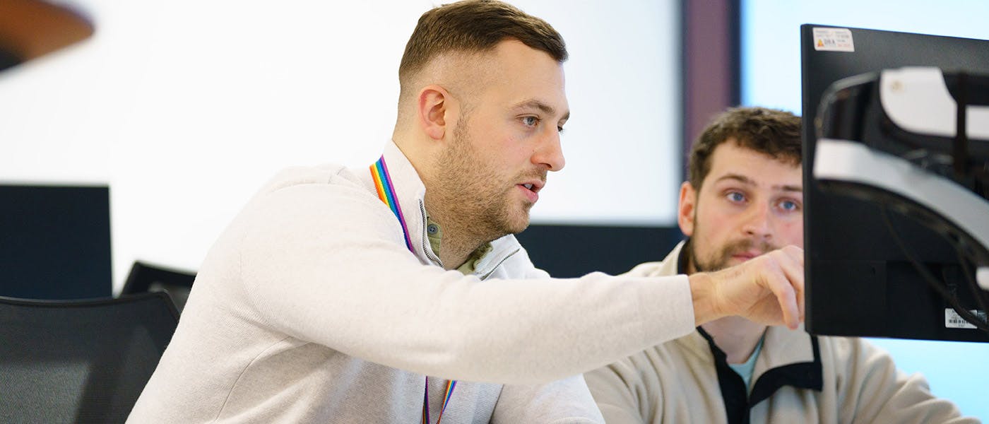 Two developers discussing code on a computer screen