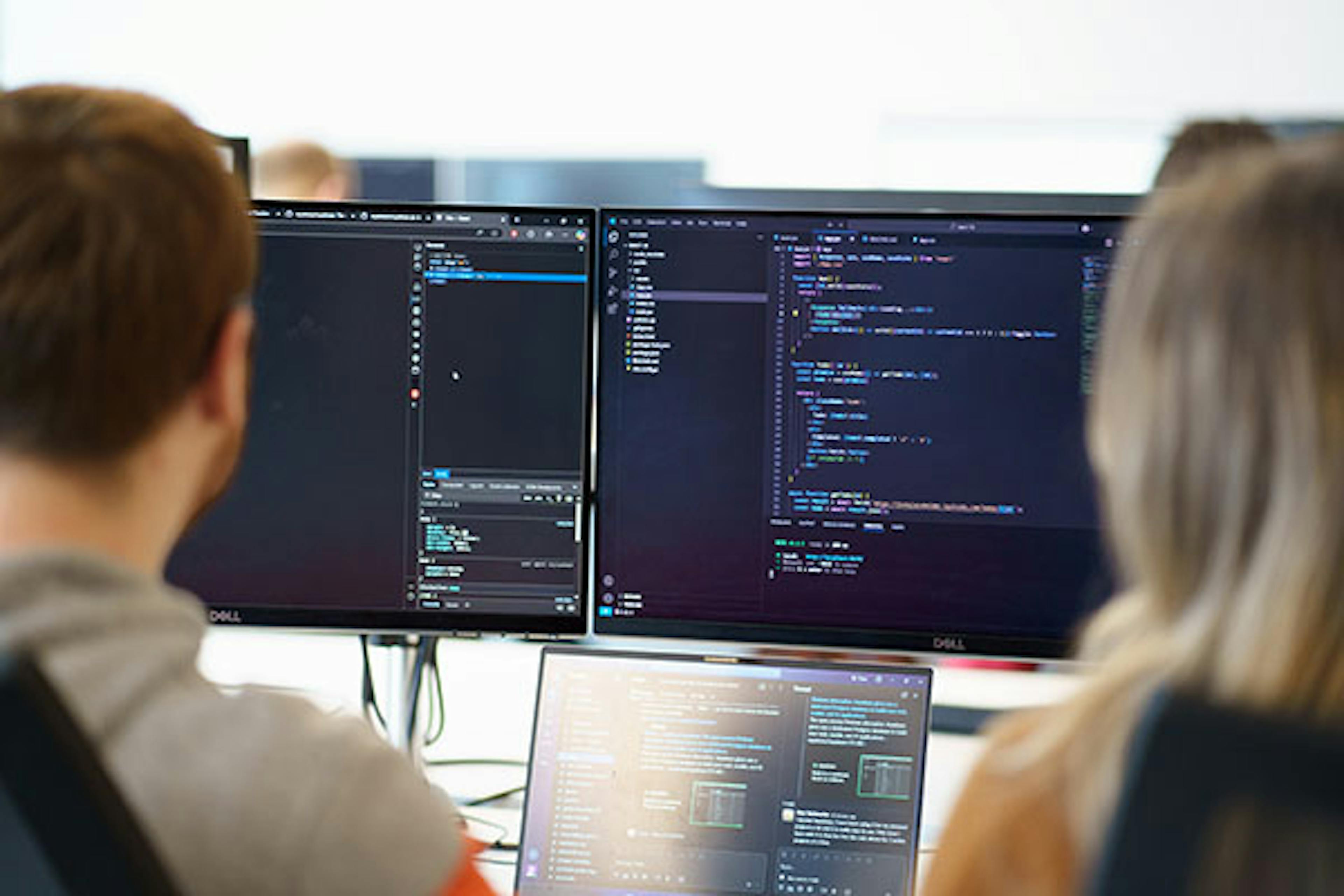 Two people looking at code on a screen