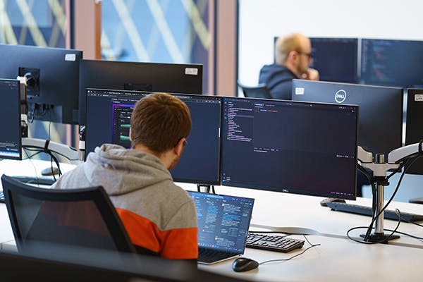 Man looking at coding on 2 monitors
