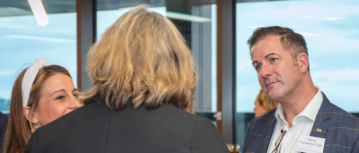 Three people engaged in conversation at a networking event.