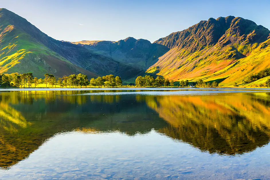 A range of hills reflected in a lake on a sunny day
