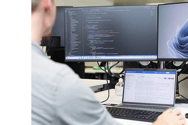 Person coding at a desk with three screens