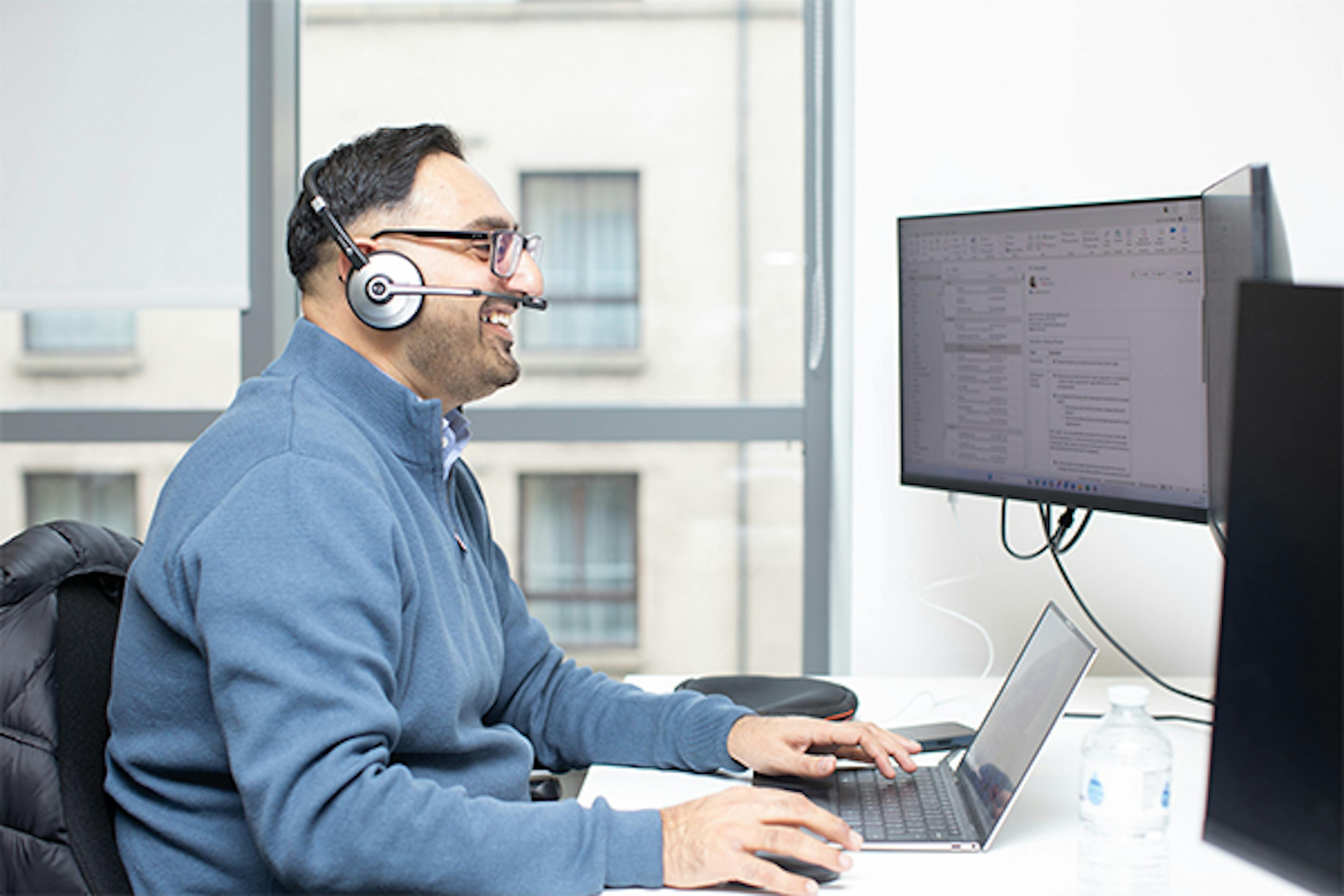 Man with headset looking at 2 monitors