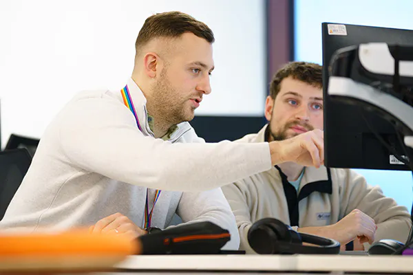 Two developers discussing some code on a computer screen