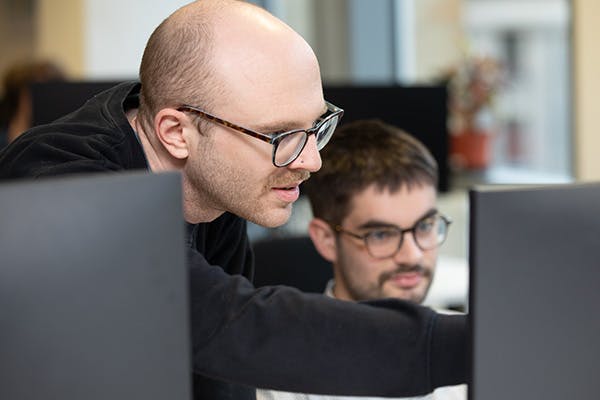 Two people in an office discussing something on a desktop screen