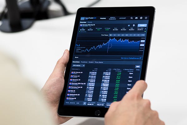 A person holding a tablet computer displaying data in text and chart formats
