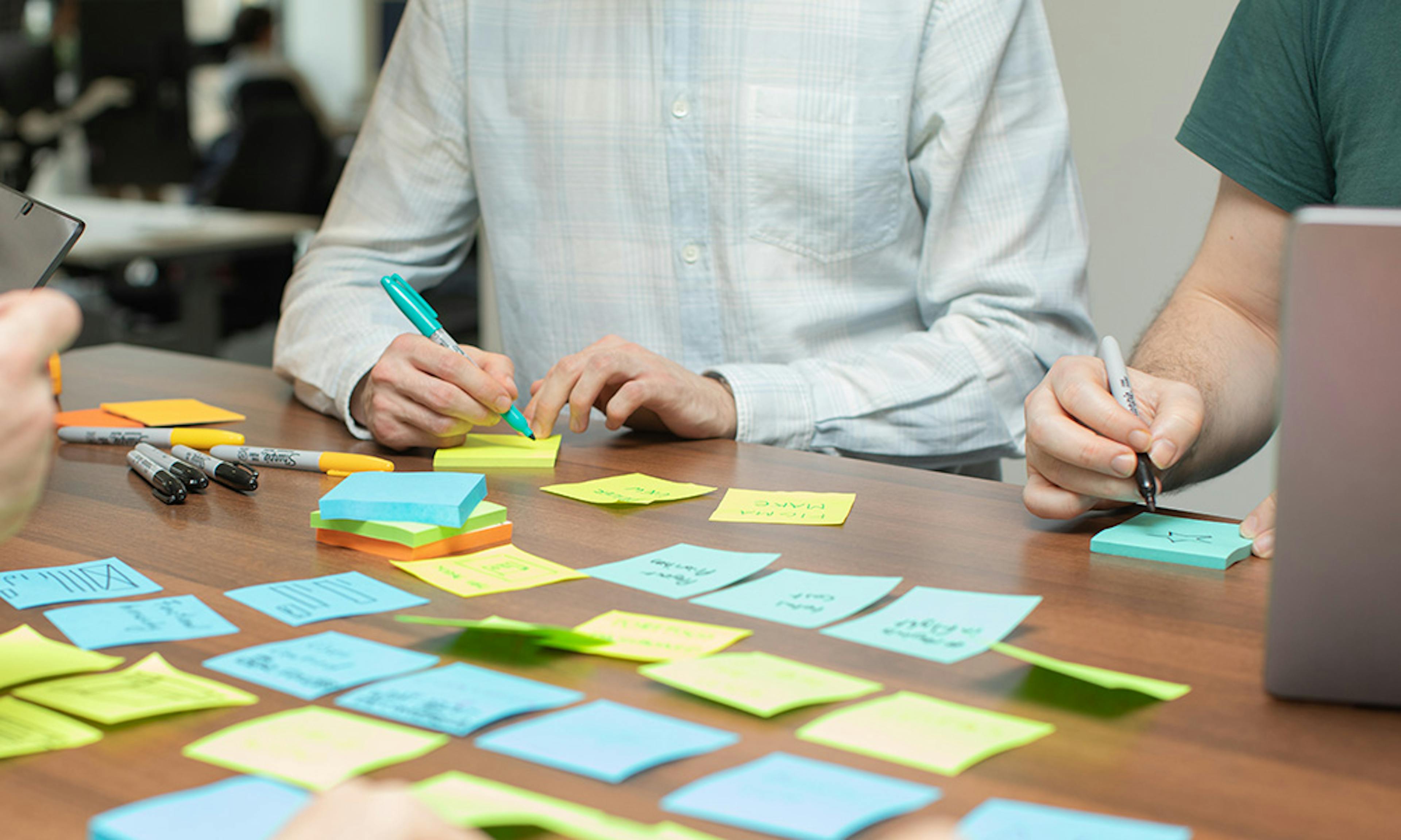 UX designers in a meeting using laptops and sticky notes