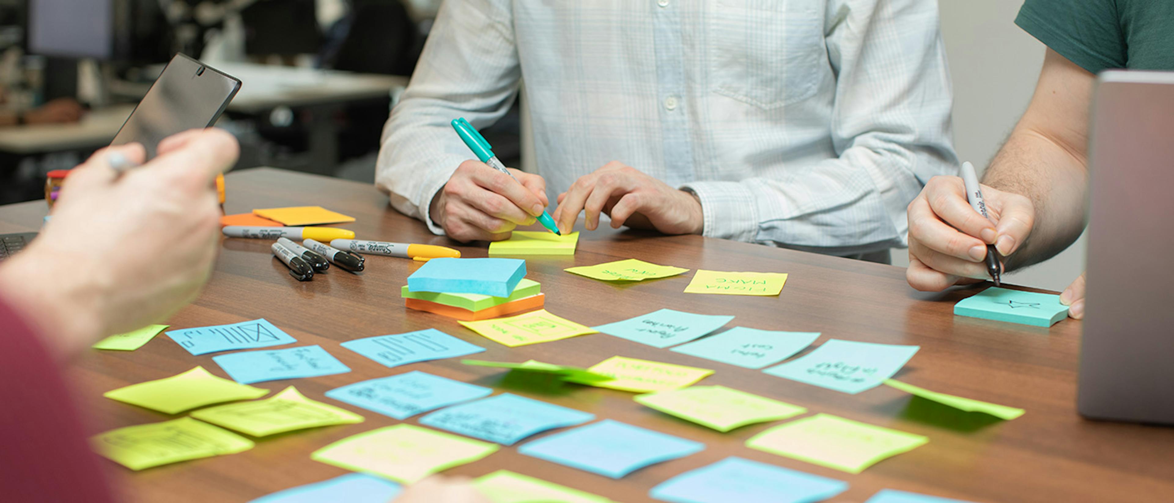UX designers in a meeting using laptops and sticky notes