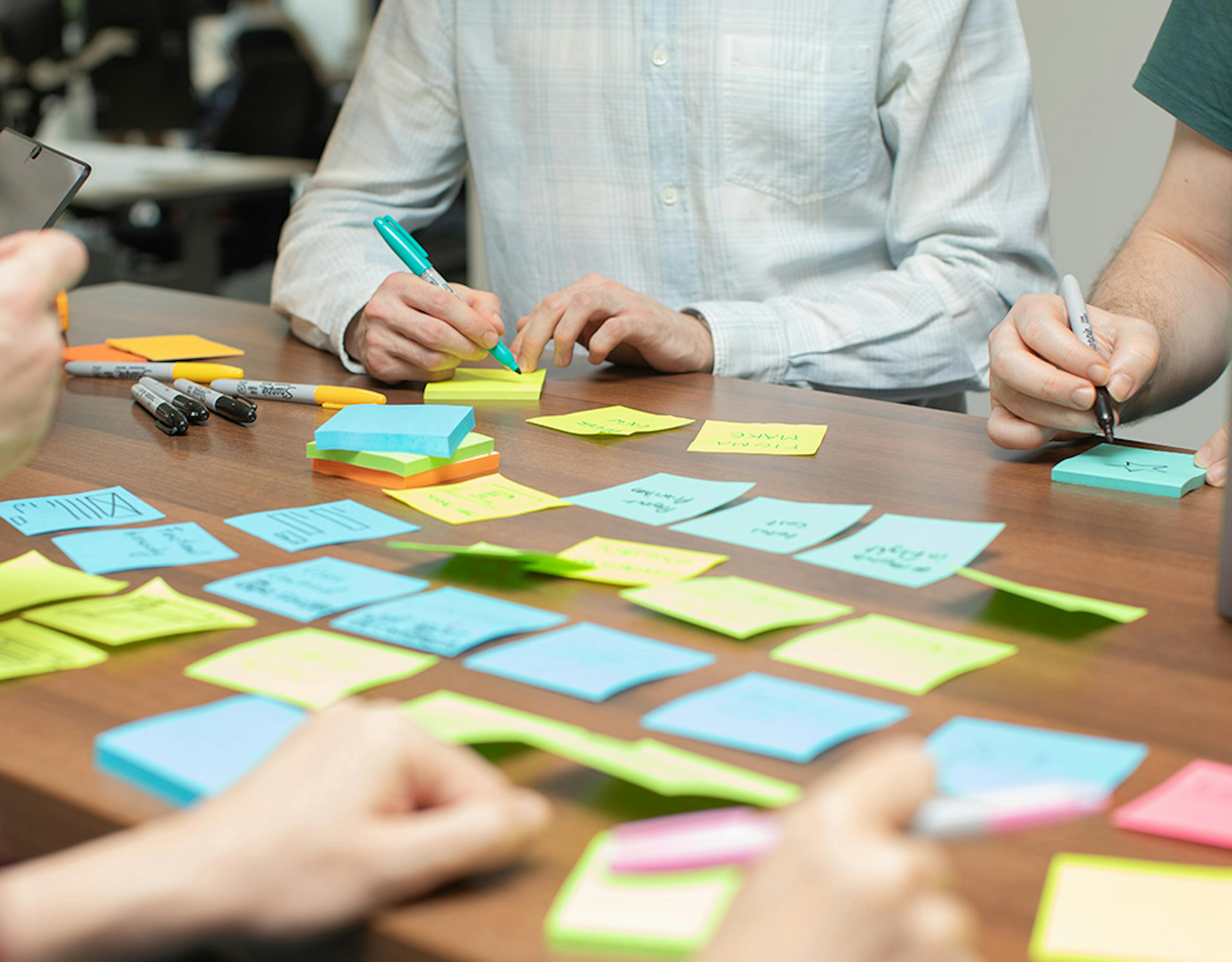 UX designers in a meeting using laptops and sticky notes