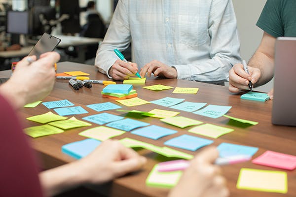 UX designers in a meeting using laptops and sticky notes