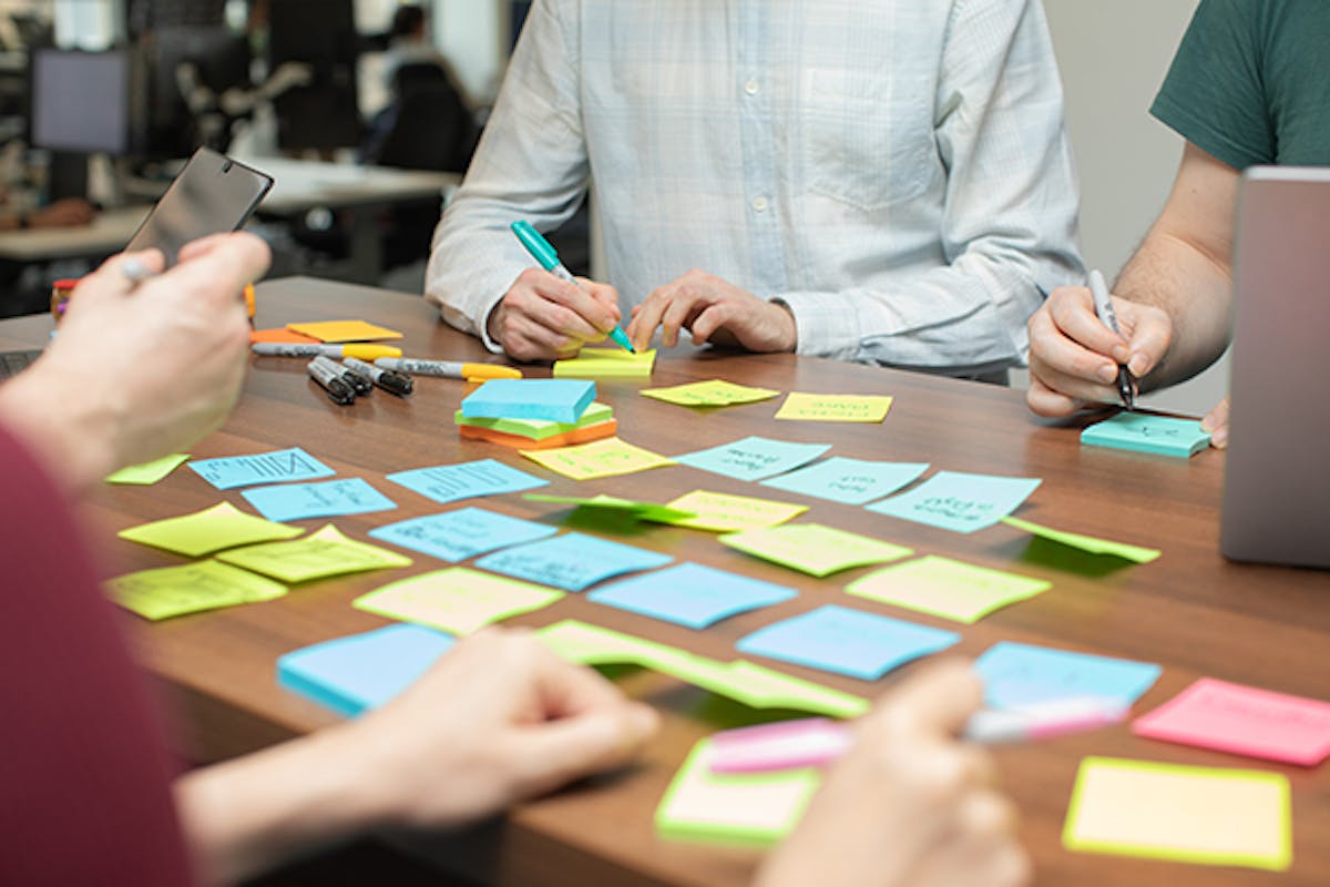 UX designers in a meeting using laptops and sticky notes