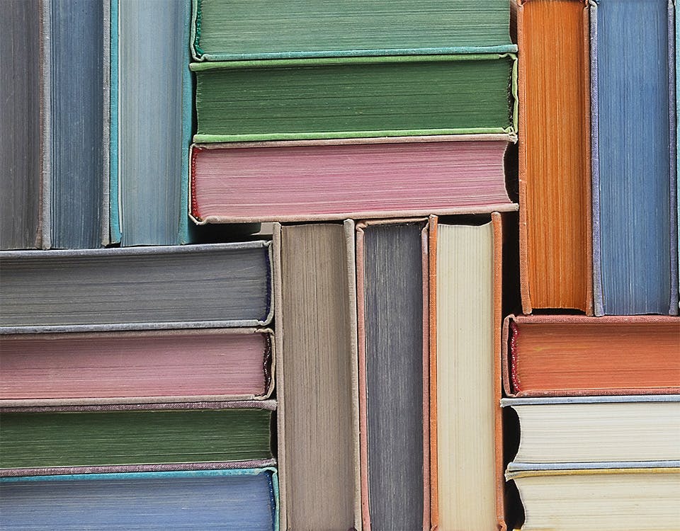 Colourful books stacked in a herringbone pattern