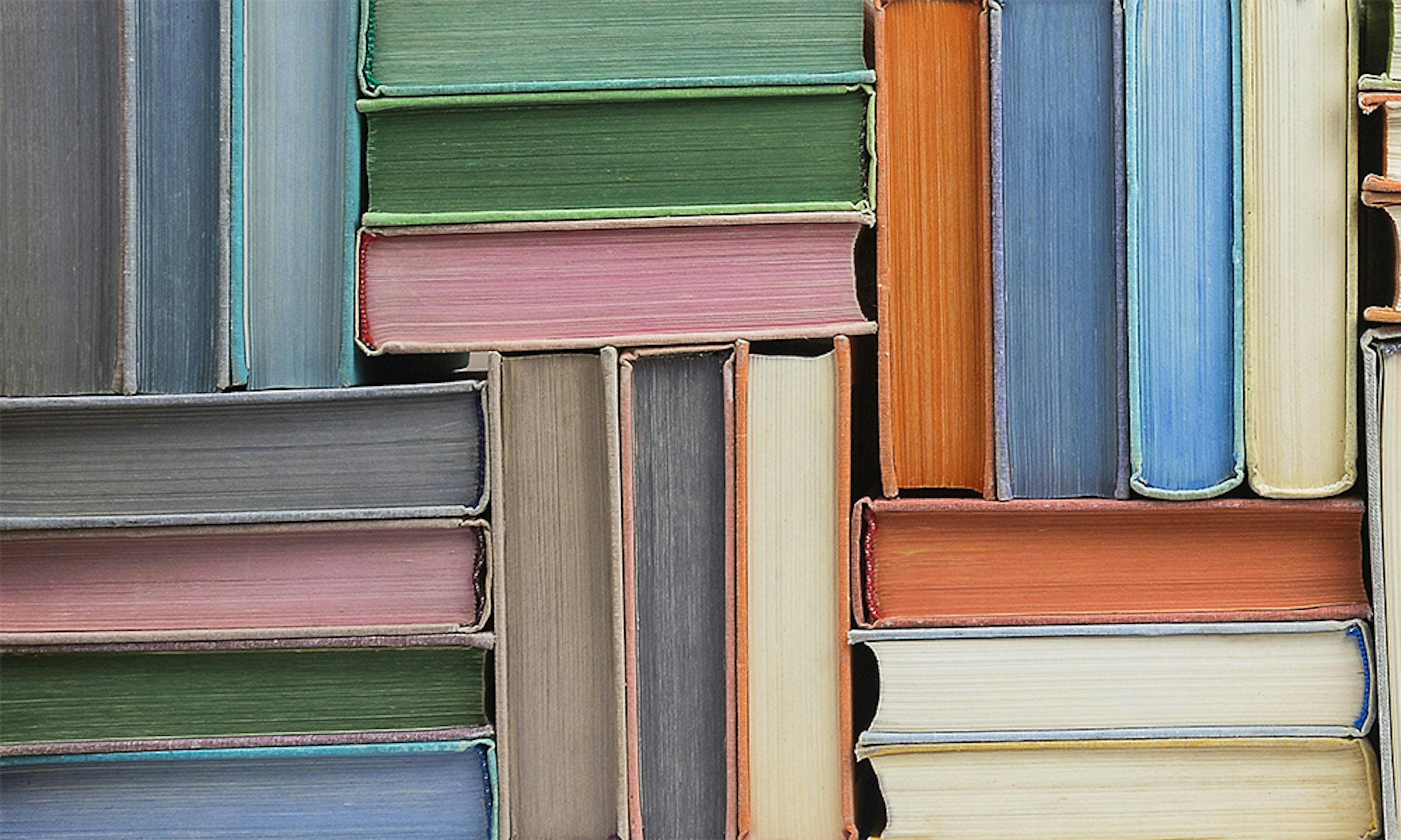 Colourful books stacked in a herringbone pattern