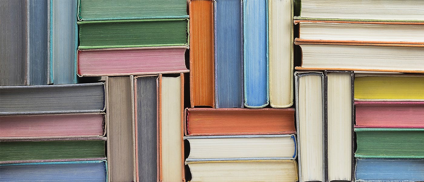 Colourful books stacked in a herringbone pattern