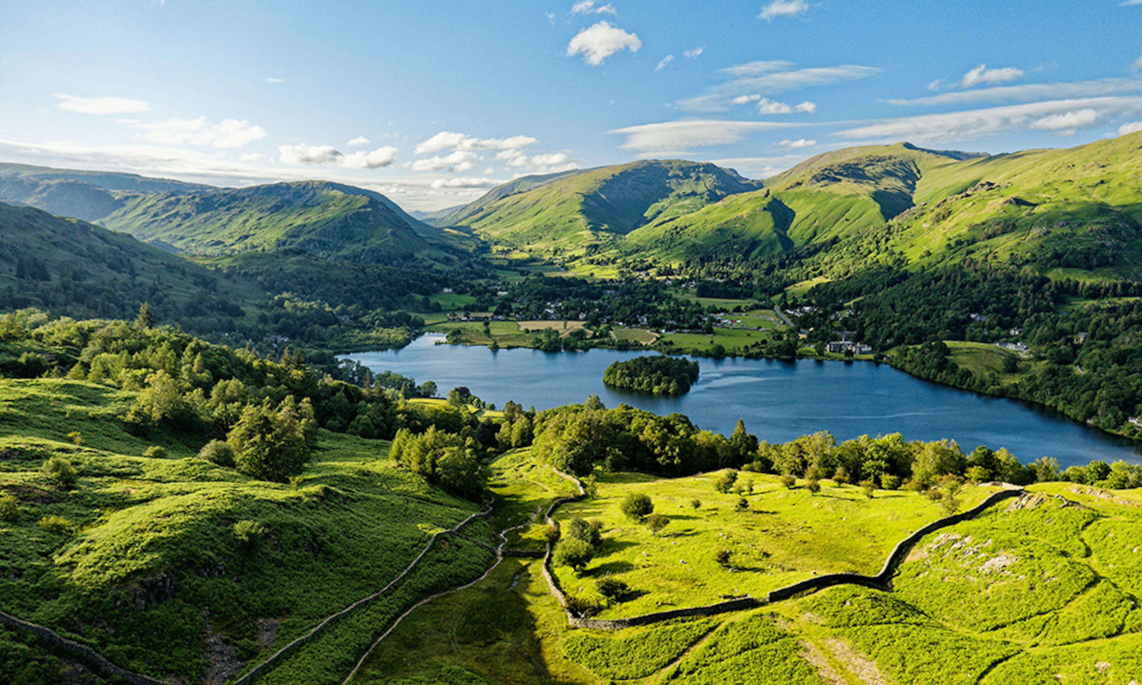 An aerial view of a lake surrounded by hills on a sunny day