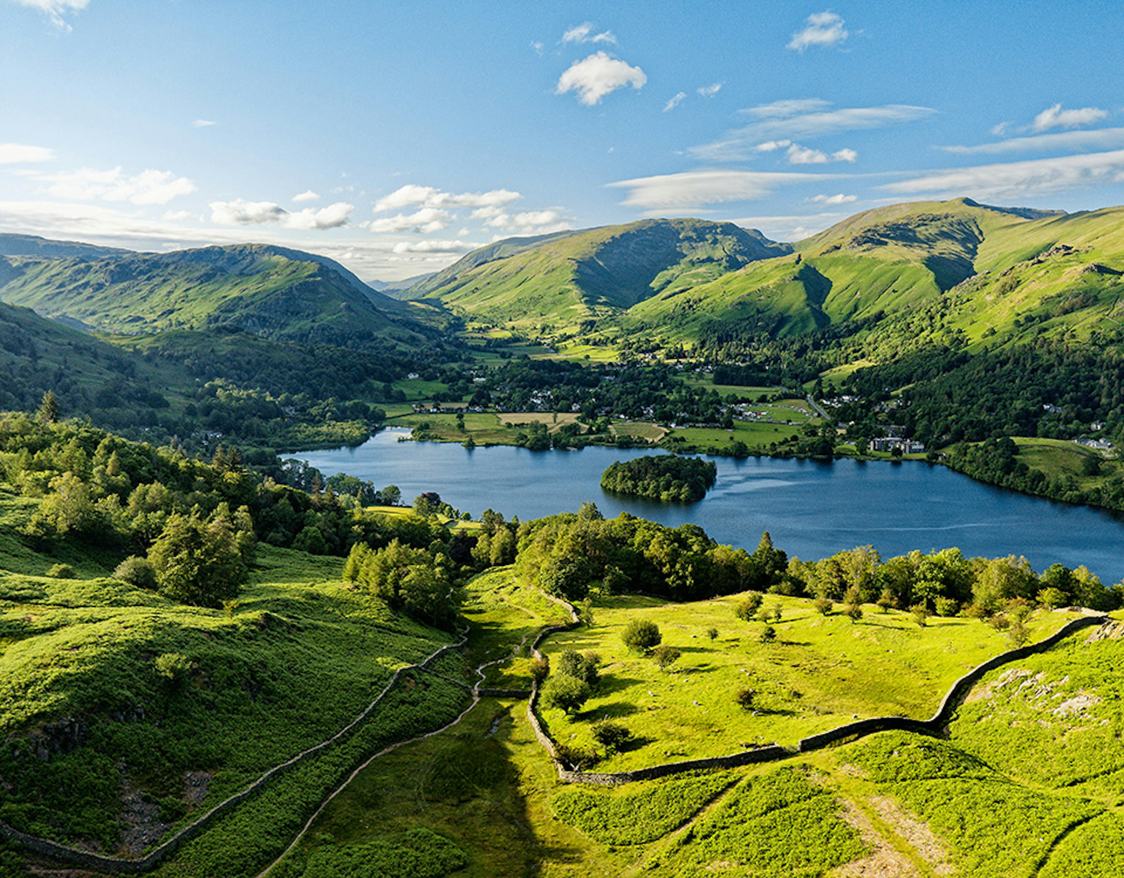 An aerial view of a lake surrounded by hills on a sunny day