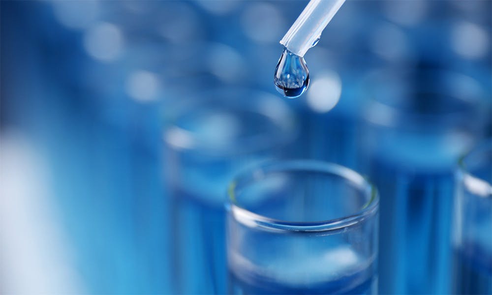 Dripping reagent into a test tube against ablurred background of test tubes