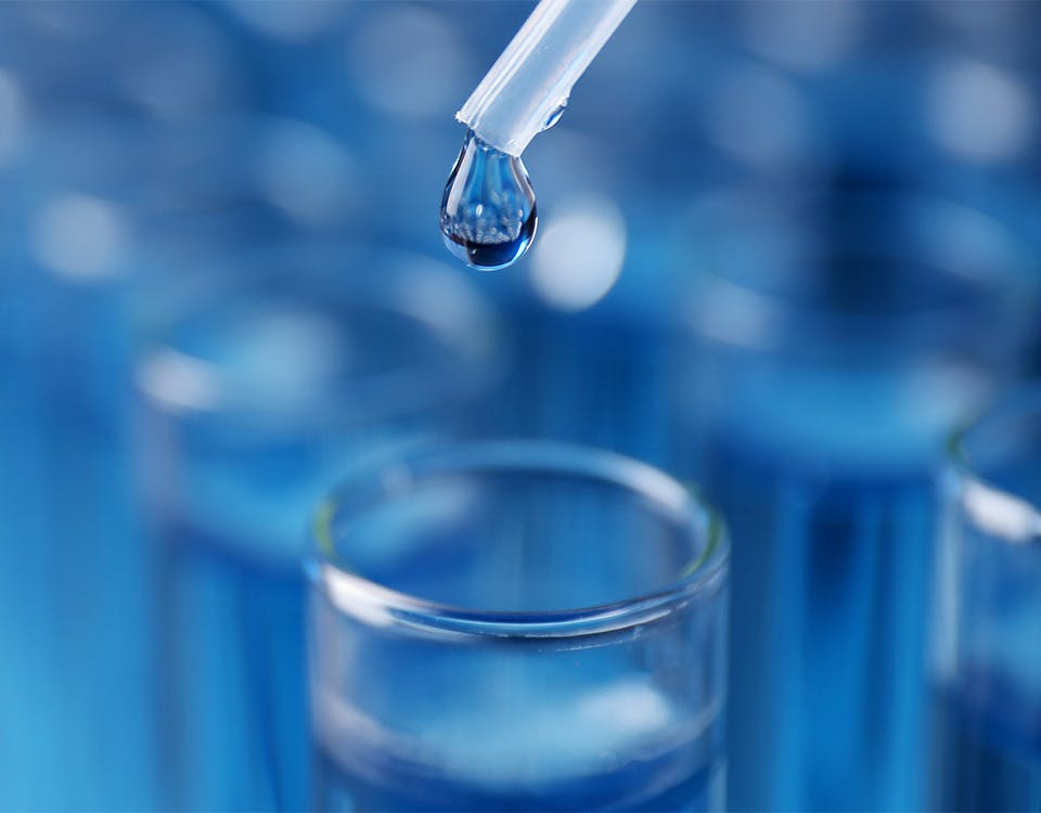 Dripping reagent into a test tube against ablurred background of test tubes