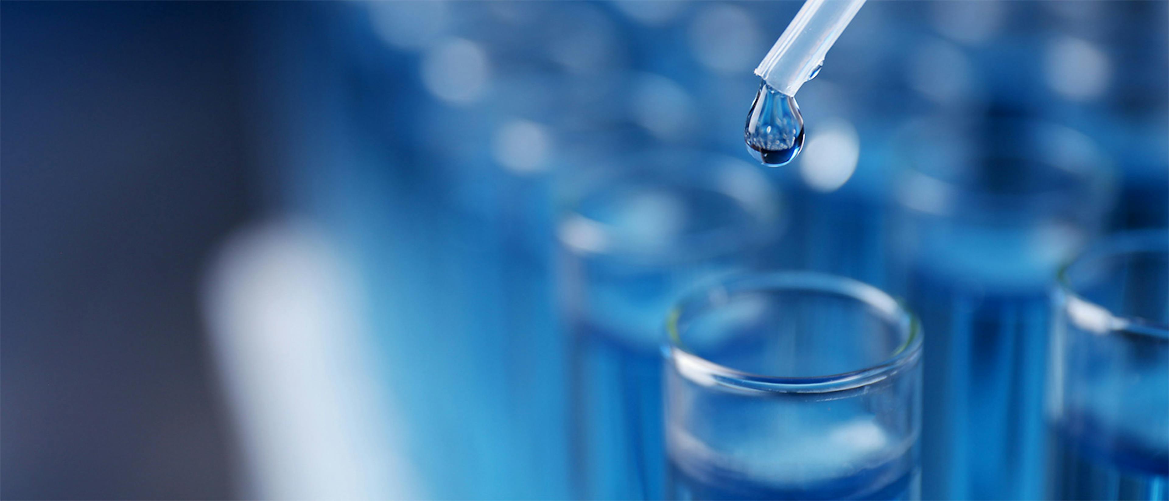 Dripping reagent into a test tube against ablurred background of test tubes