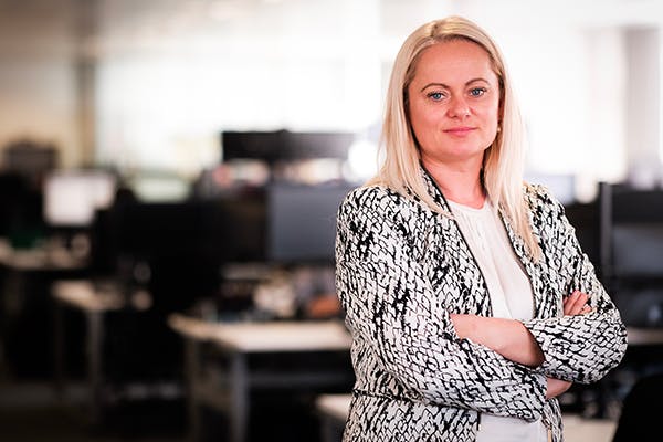 Person stands arms crossed in front of desks