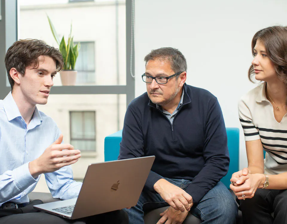 Three people discussing around a laptop