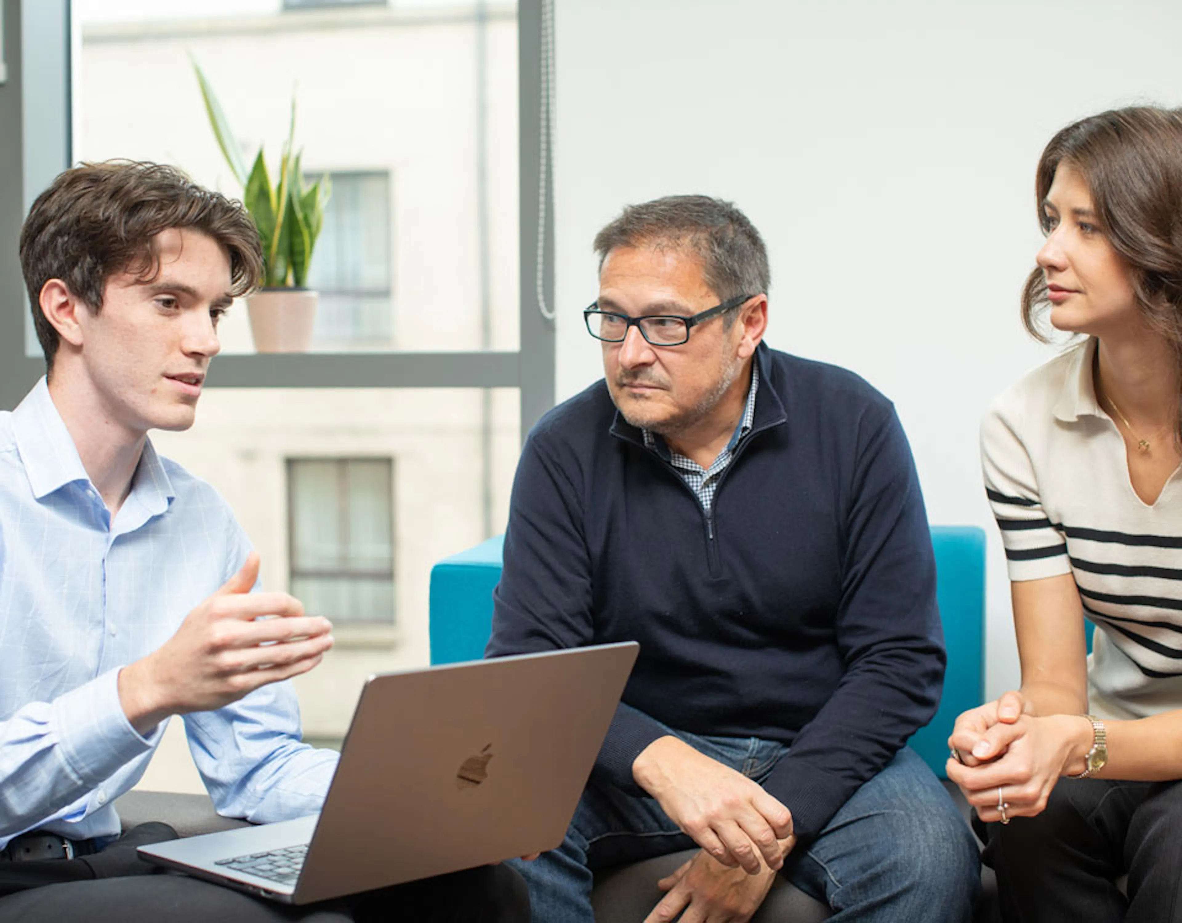 Three people discussing around a laptop