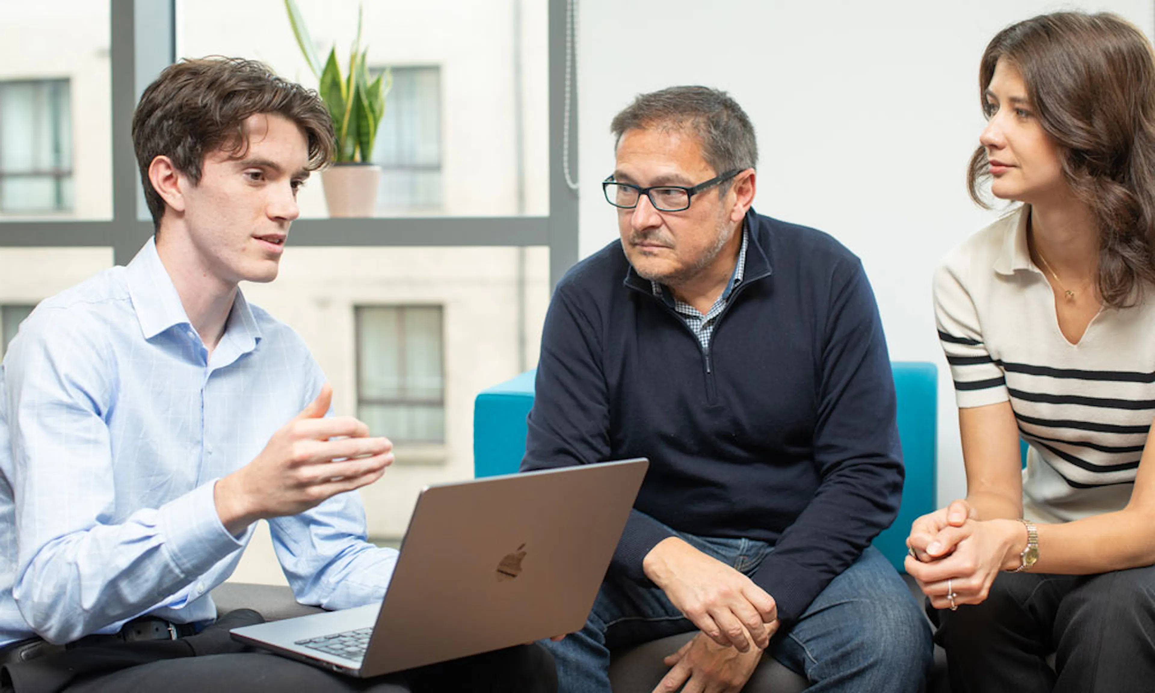 Three people discussing around a laptop