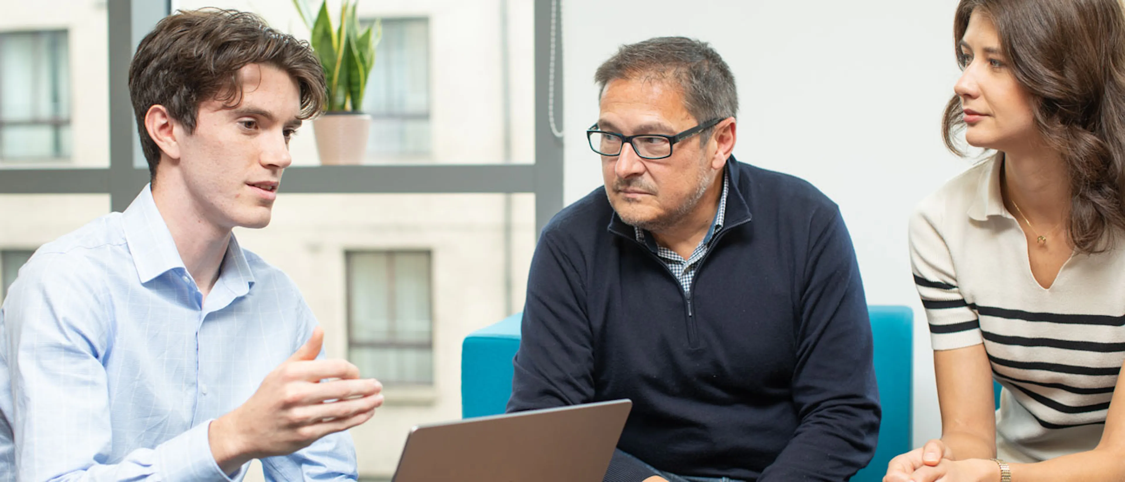 Three people discussing around a laptop