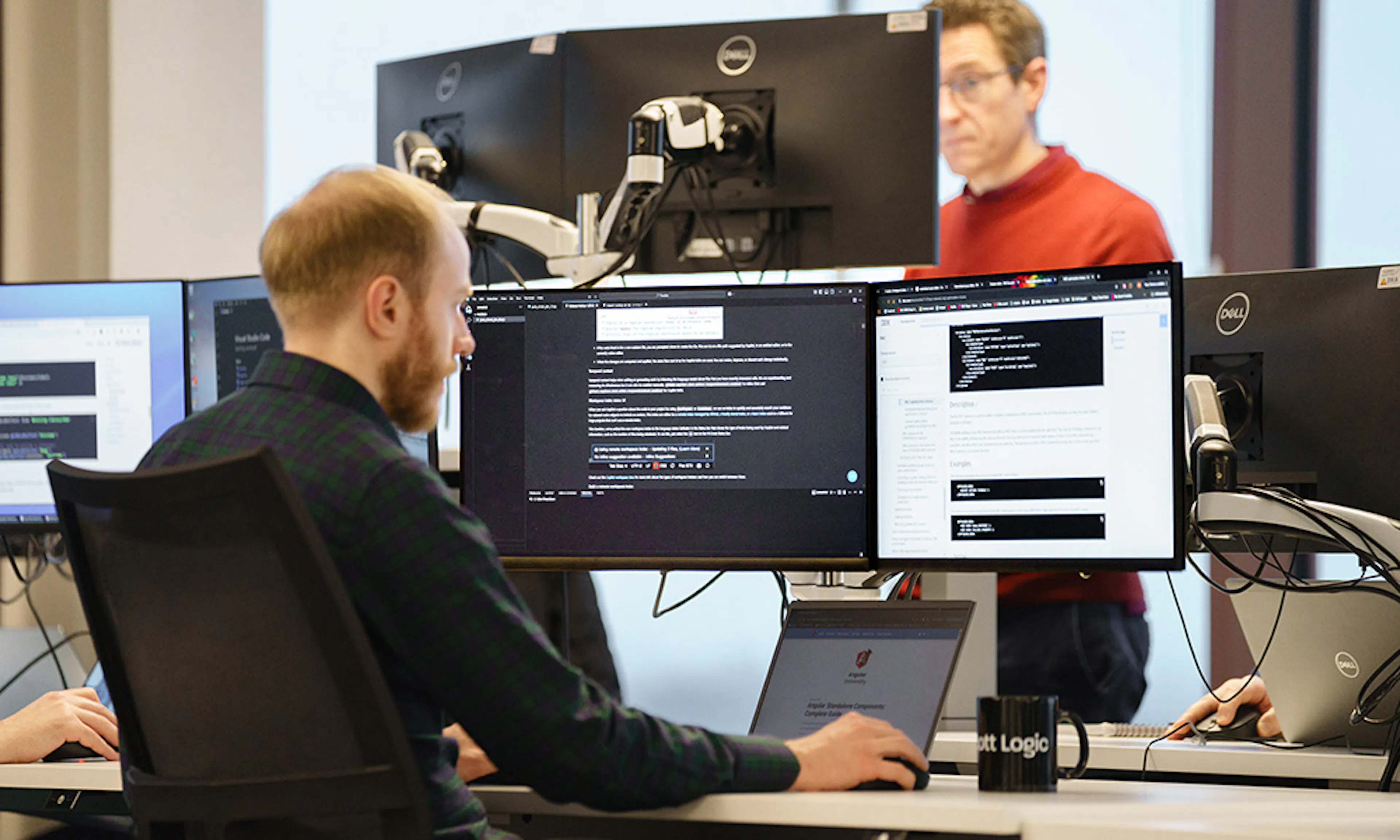 A developer in an office setting, working with three screens