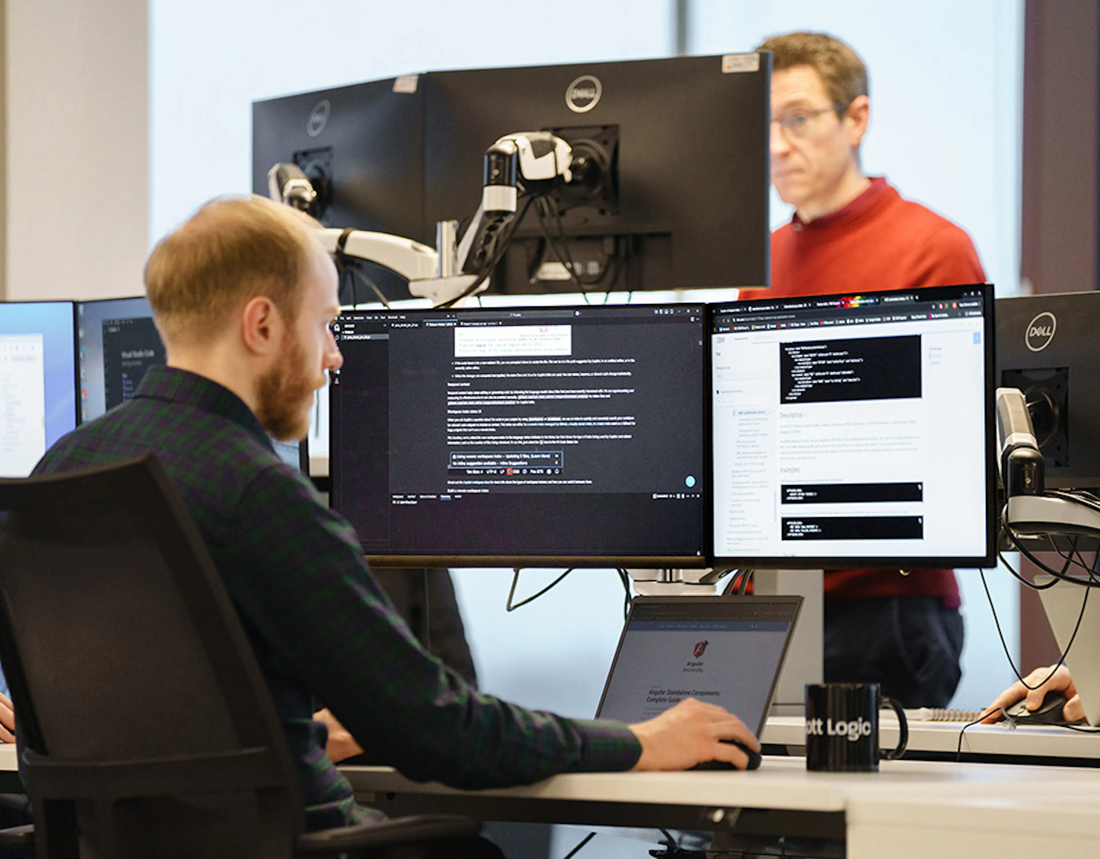 A developer in an office setting, working with three screens