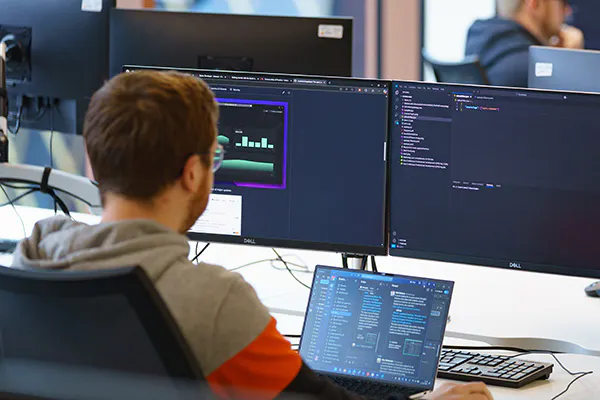 Developer working with three screens in an office setting
