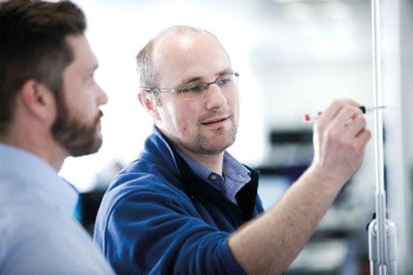 Photo of two men writing on a whiteboard