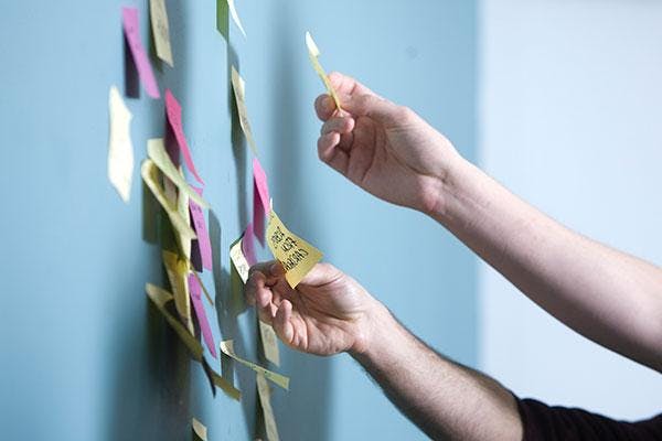 Hands posting sticky notes on a board