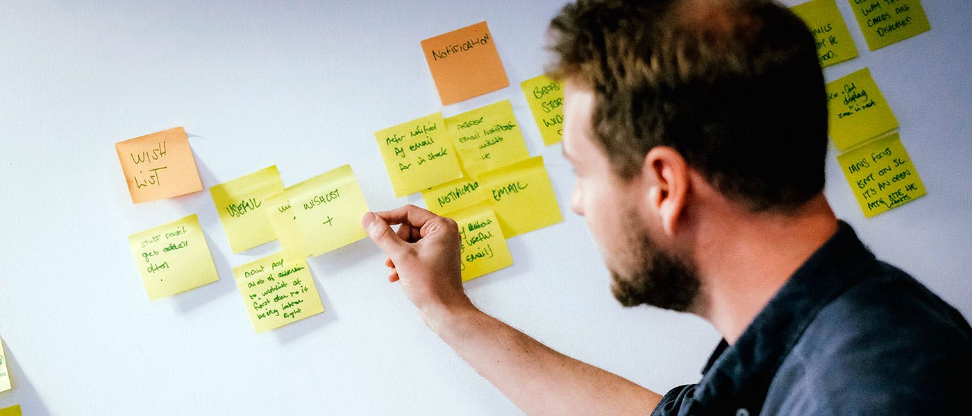 Man adding sticky notes to a wall