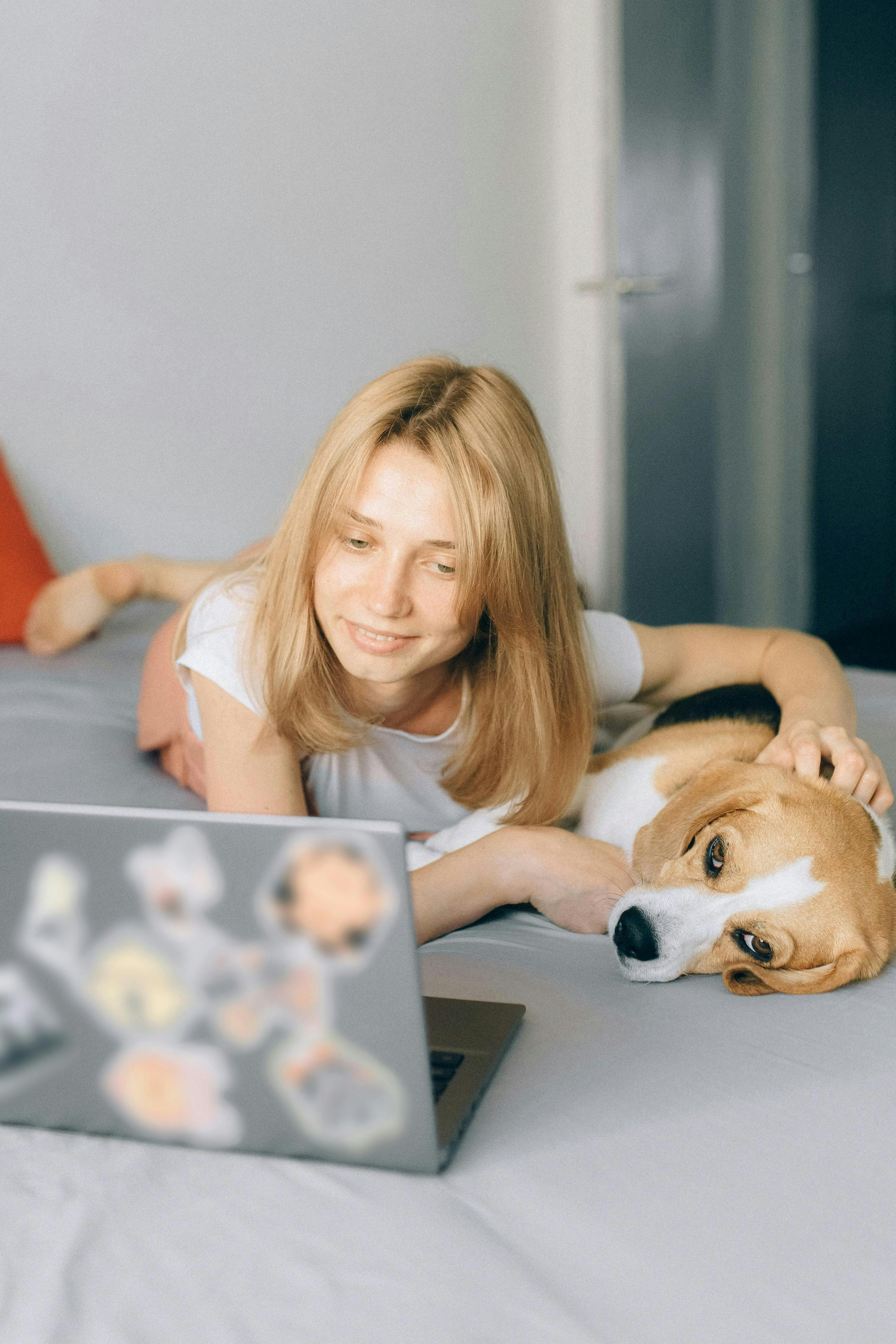 A woman looks at her computer while her beagle lies next to her