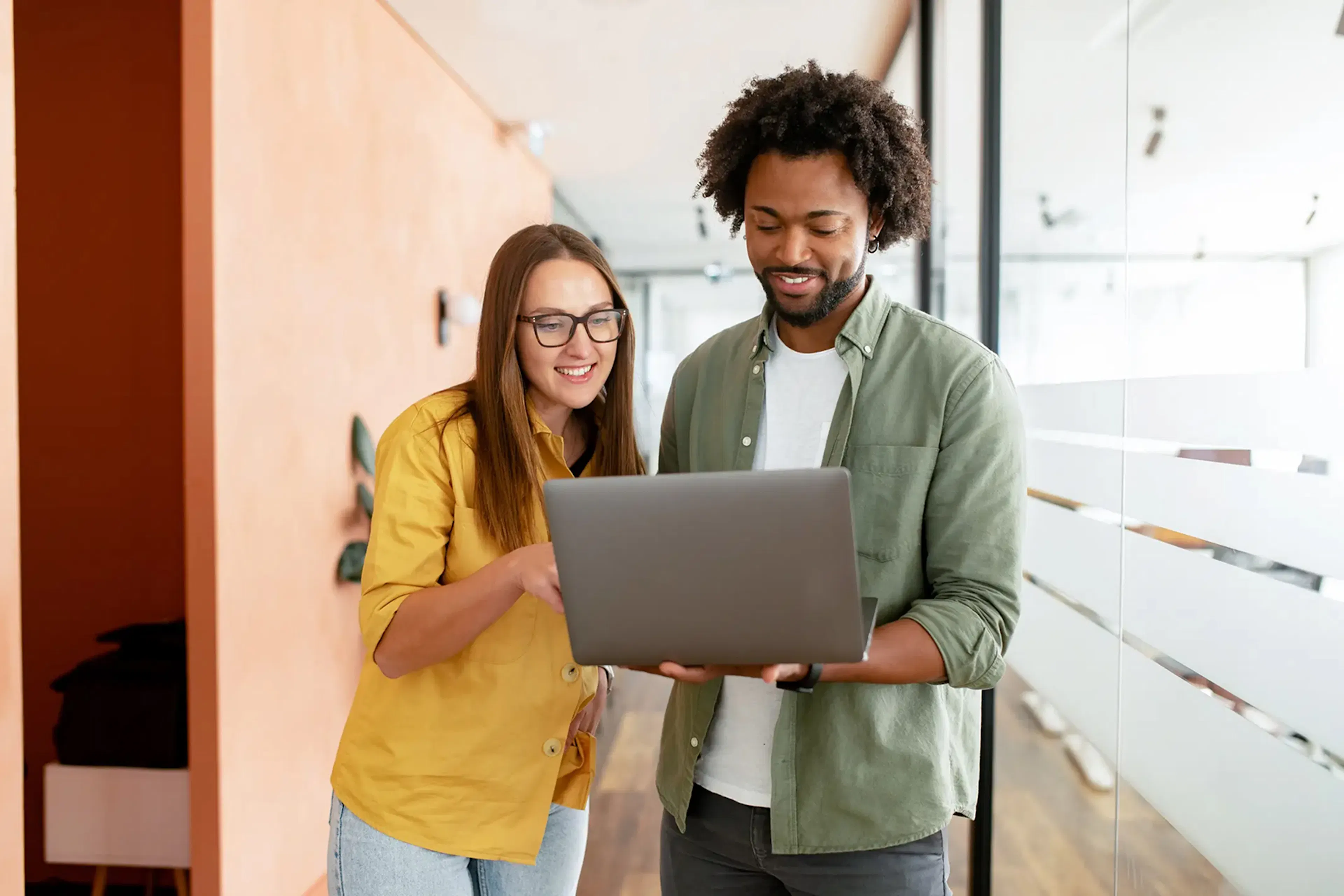 two people looking at a laptop screen and smiling