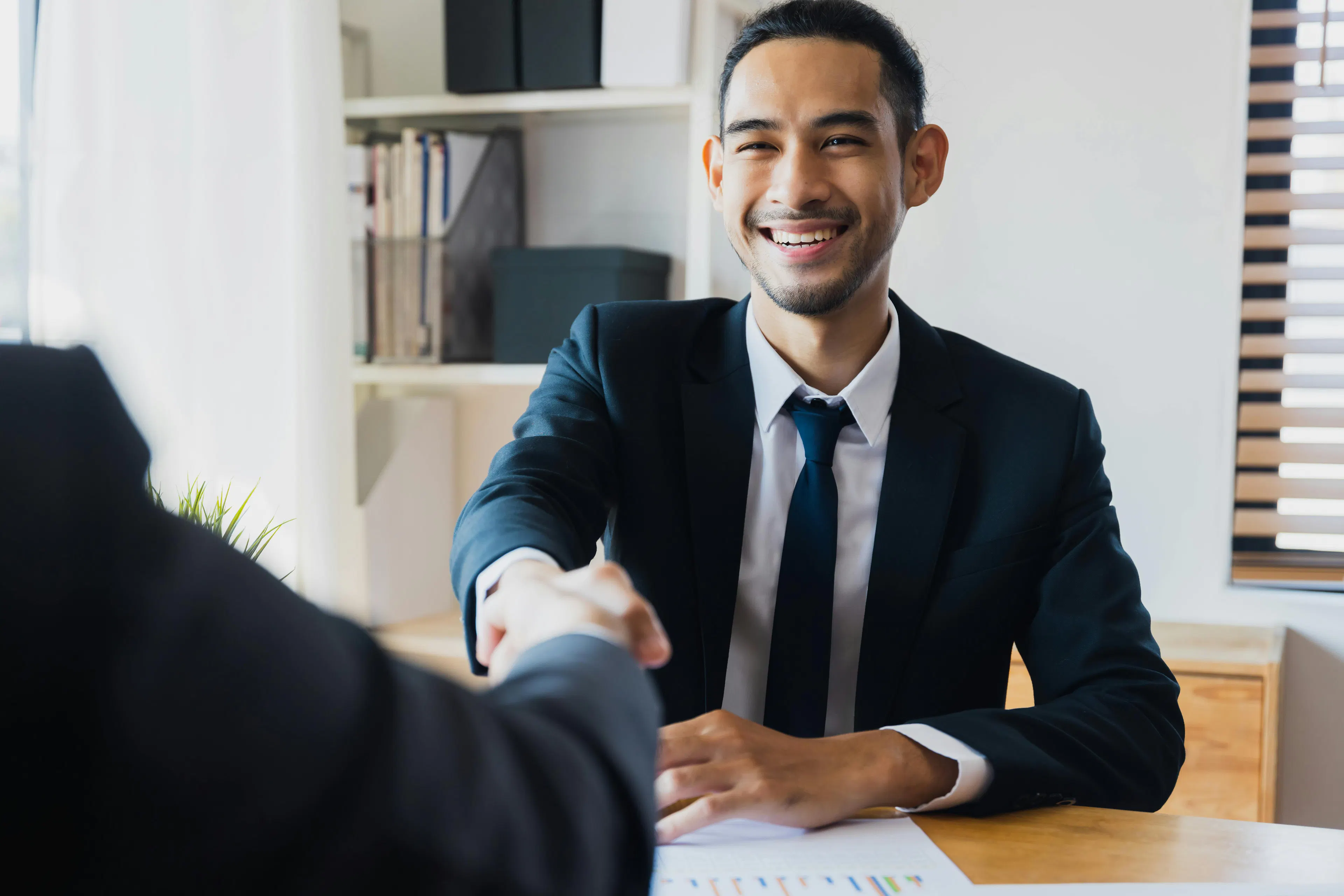 men shaking hands over a desk