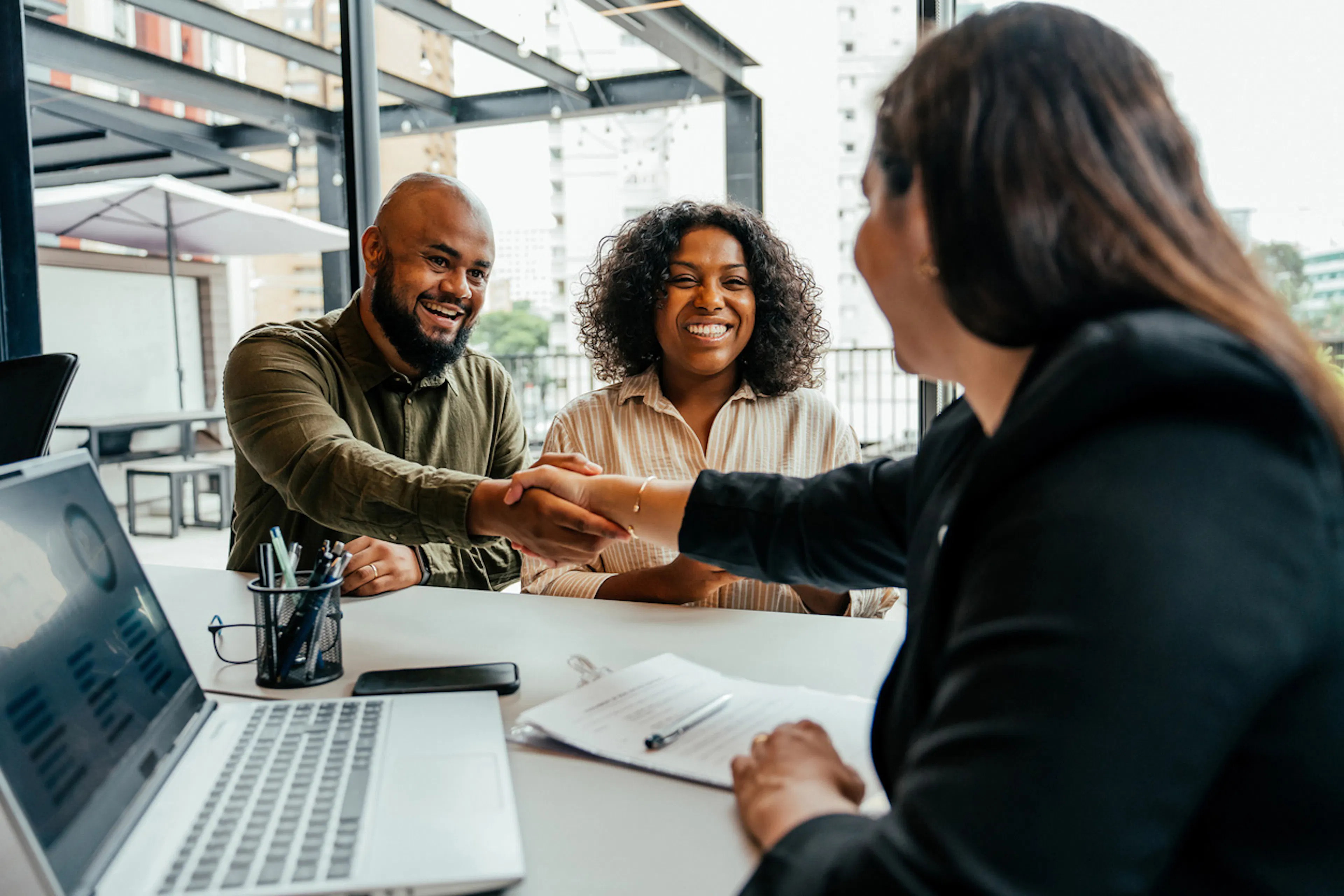 banker shaking hands over desk with two clients
