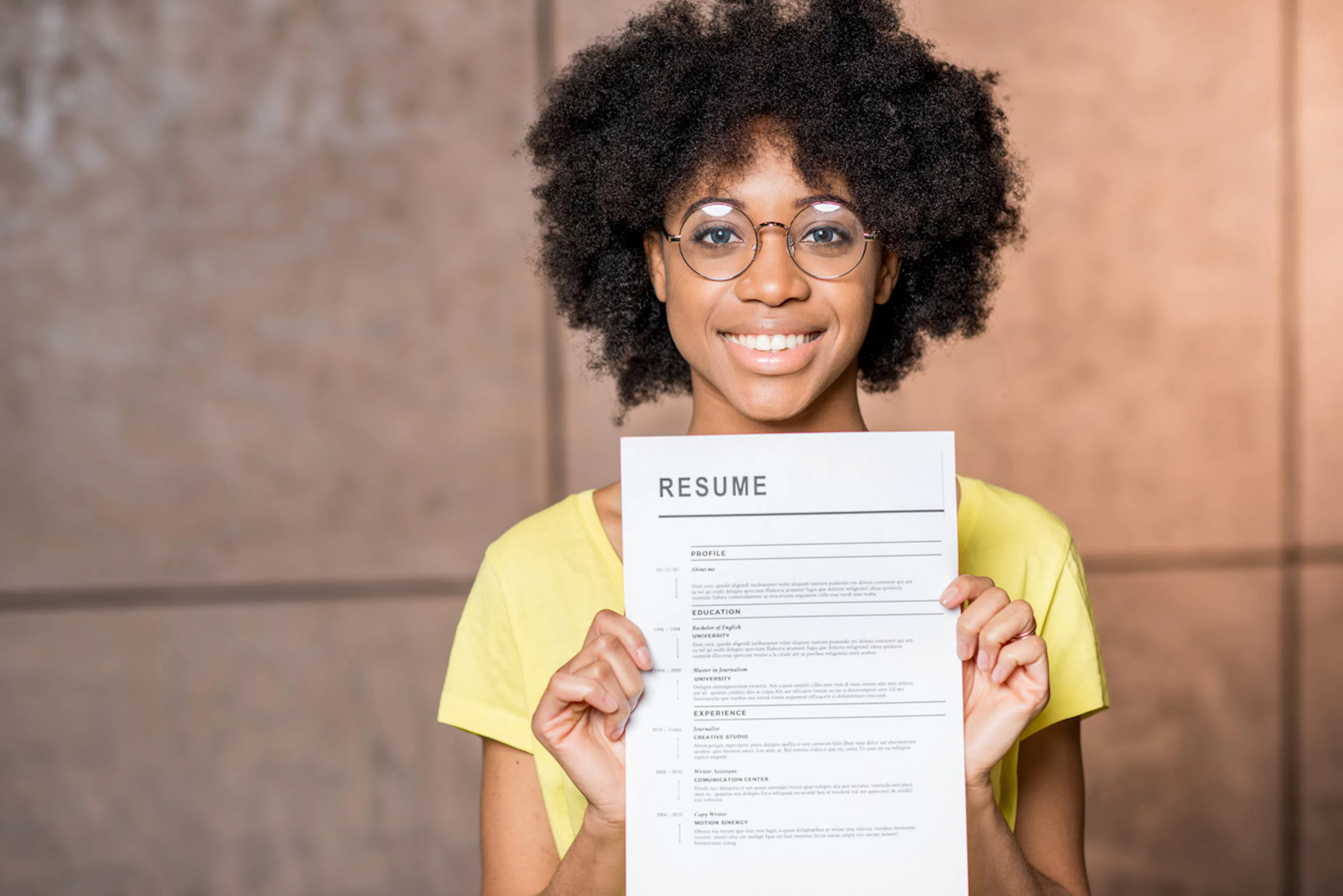 woman wearing glasses holding up a resume