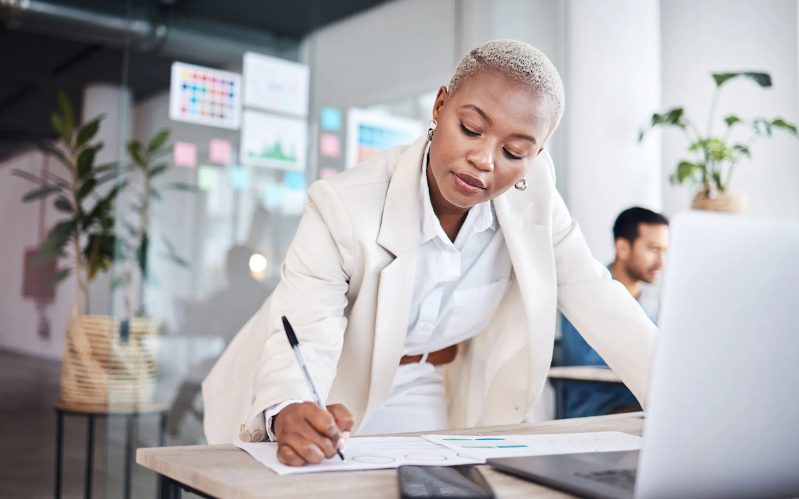 professional woman taking notes in front of a laptop