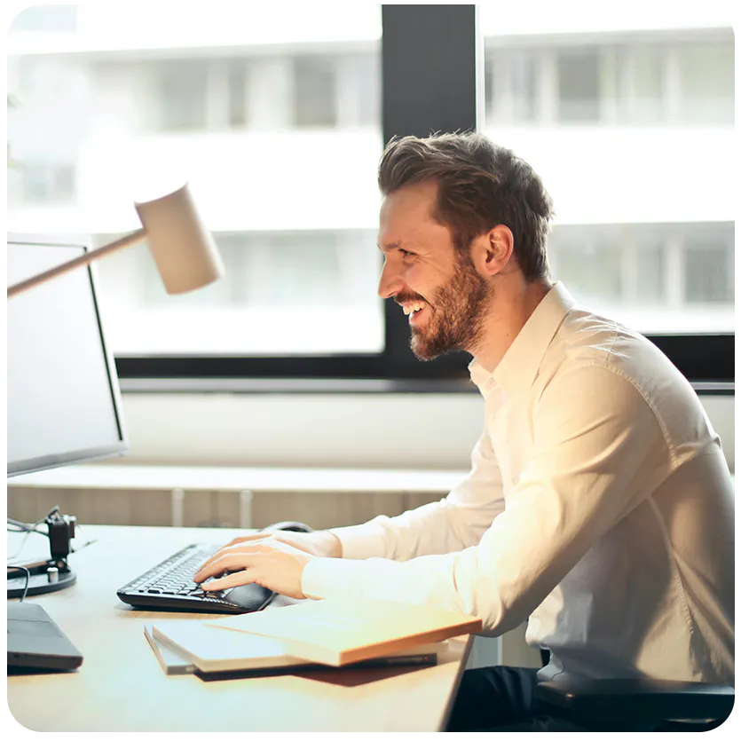 man working on a computer and smiling