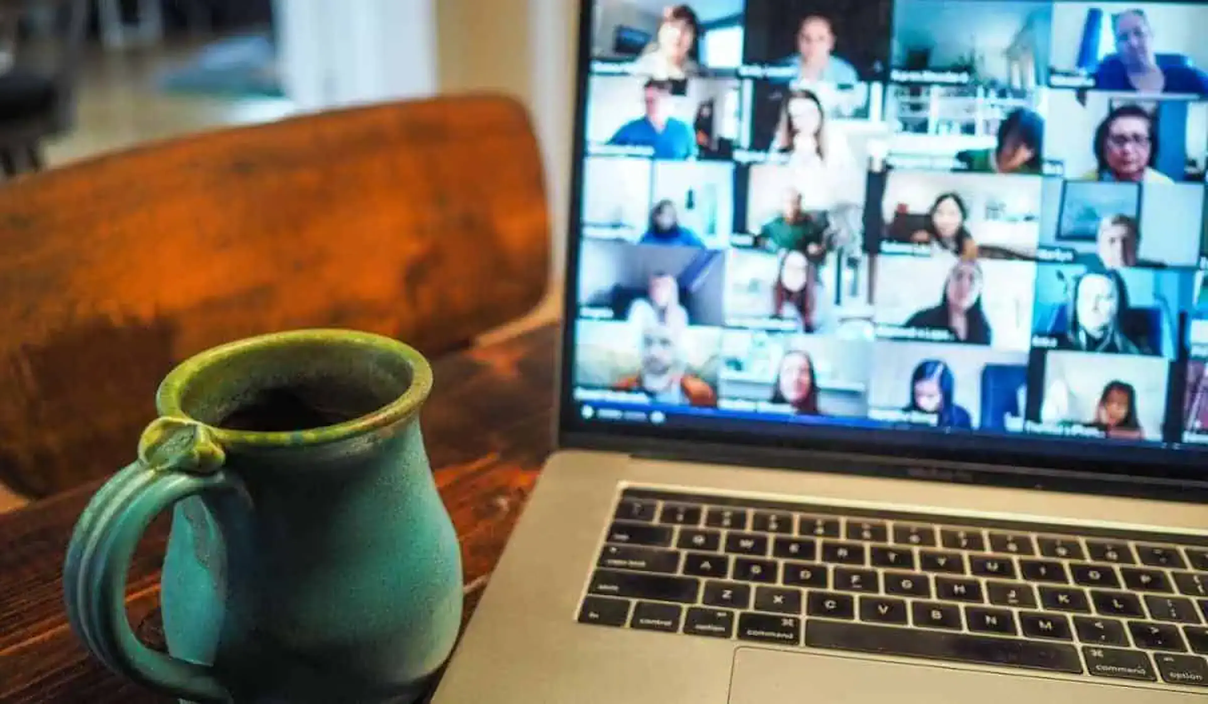 laptop showing video meeting with coffee mug on desk