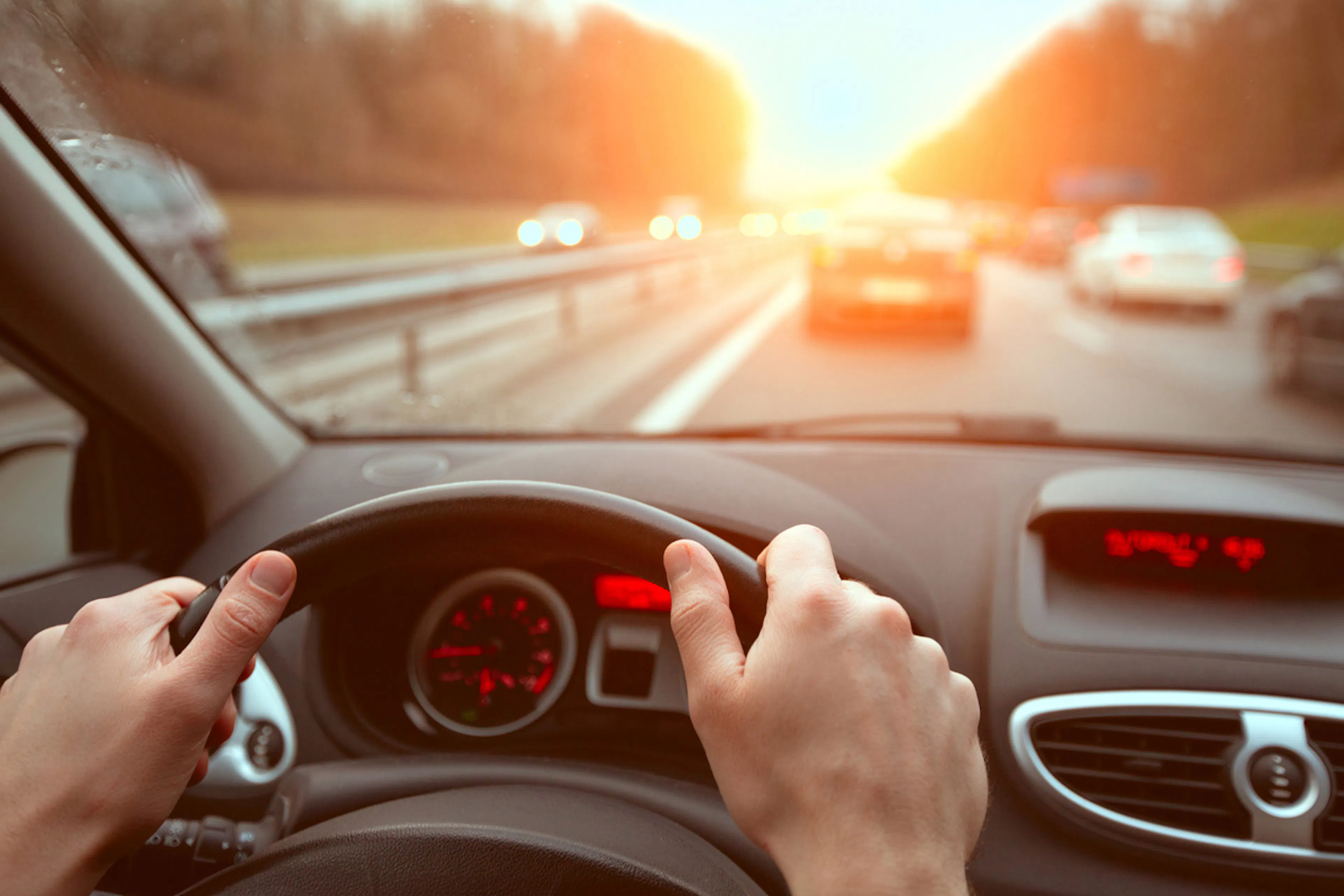 person driving down the highway with sun on the horizon