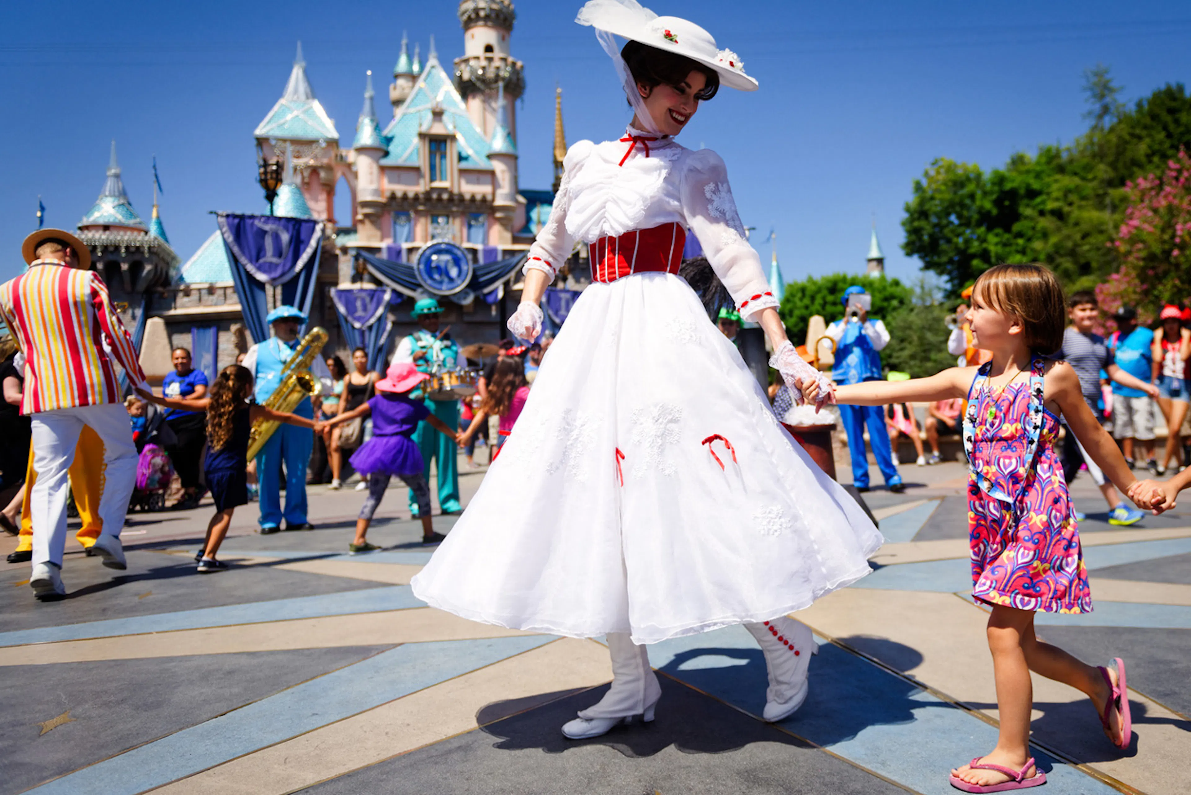 theme park worker dressed as princess holding little girl's hand